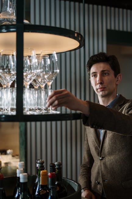 Sommelier in a stylish bar selecting wine glassware from glass display. Ideal for hospitality and lifestyle imagery.