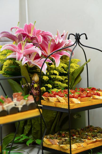 A stylish catering display with appetizers and vibrant floral arrangement.