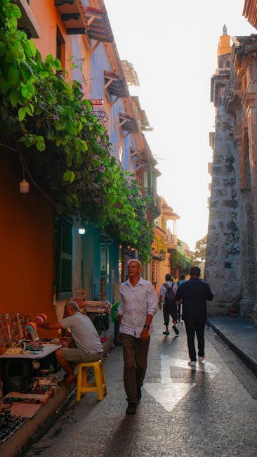 Vibrant street in Cartagena's historic center with people walking, showcasing colorful architecture.