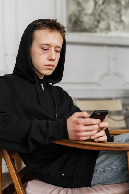 teen sitting with smartphone looking thoughtful indoors worried expression
