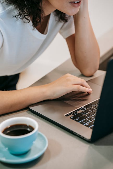 Woman working on a laptop at home with a cup of coffee, showcasing modern freelance work lifestyle.