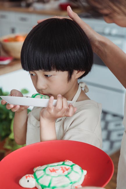 Asian child decorating cookies in a cozy home kitchen, enjoying a culinary creative activity.