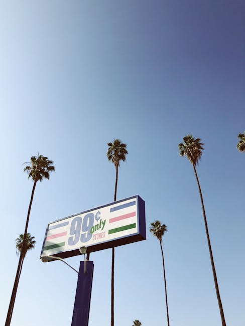 99 Cents Only Store sign under a clear blue sky with tall palm trees.