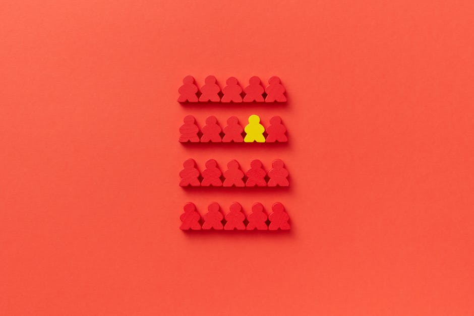 A standout yellow game piece among red pieces on a red background highlighting individuality.