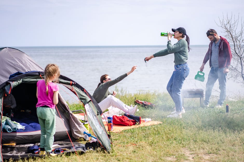 A family relaxes by the lakeside enjoying a camping picnic on a sunny day.