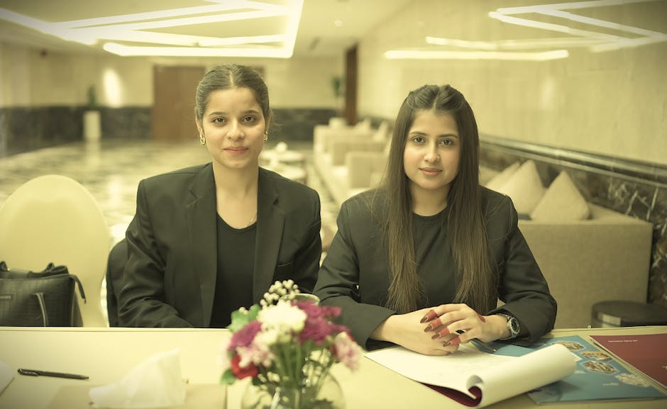 Two professional women seated at a table in a conference room, showcasing confidence and teamwork.