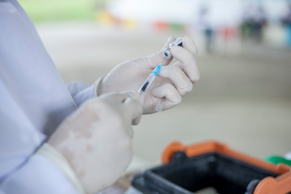 Close-up of a healthcare worker preparing a vaccine syringe in a clinical setting.