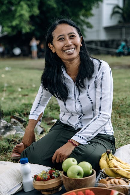 Woman enjoys a relaxing picnic outdoors with fresh fruits, exuding happiness and warmth.