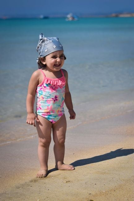 Adorable child in colorful swimsuit enjoying sunny day at the beach.