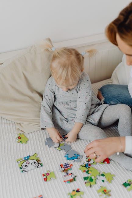 A young blonde child solving a colorful puzzle indoors with an adult. Bright and playful scene.