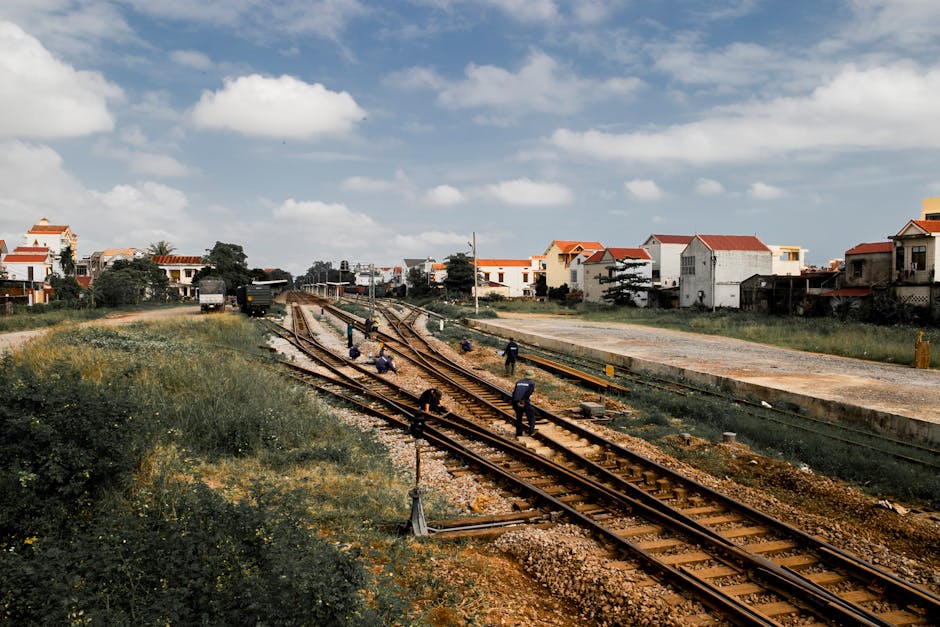 Workers maintaining railroads in a rural town under blue skies.