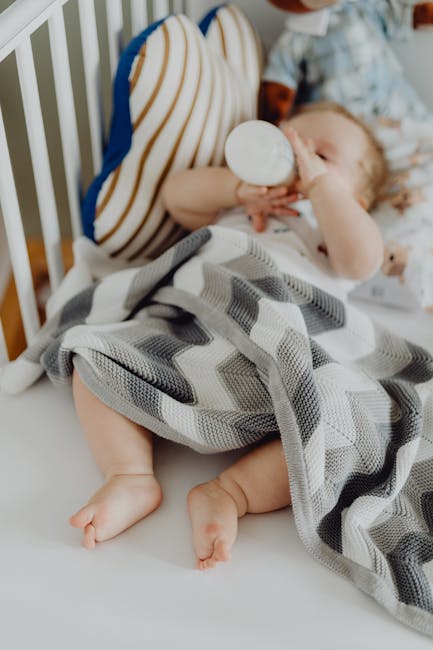 A sleeping baby with a blanket and bottle in a crib. Capturing childhood innocence and serenity.