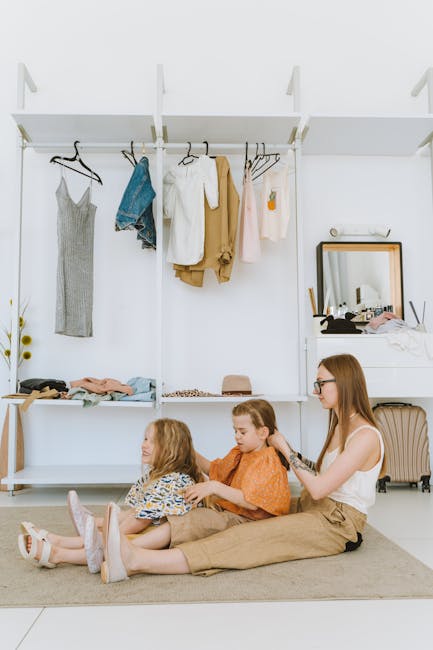 A mother braiding hair of her two daughters in a modern wardrobe area with clothes.