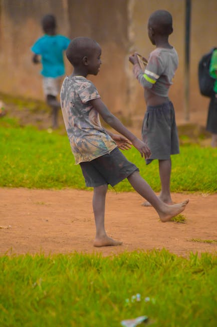 Joyful kids playing soccer on a dirt field, showcasing teamwork and leisure in an outdoor setting.