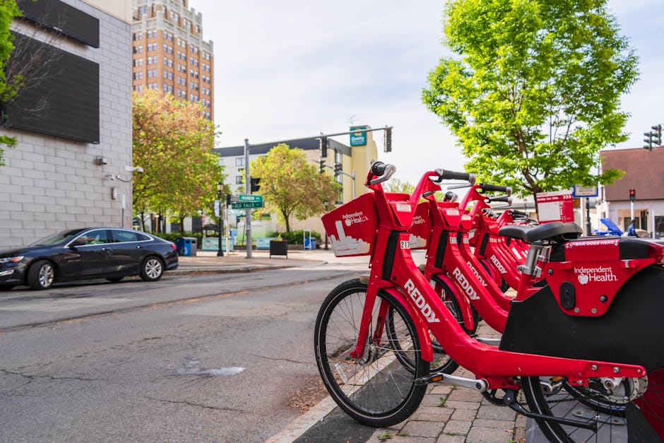 Red Reddy bikeshare bicycles lined up on a sunny city street in Niagara Falls, promoting eco-friendly urban transportation.