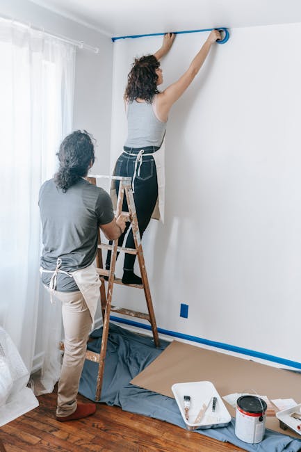 Young couple working together on home renovation, painting walls.