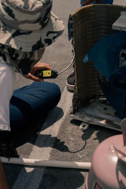 technician placing R290 propane warning label on HVAC unit, close-up