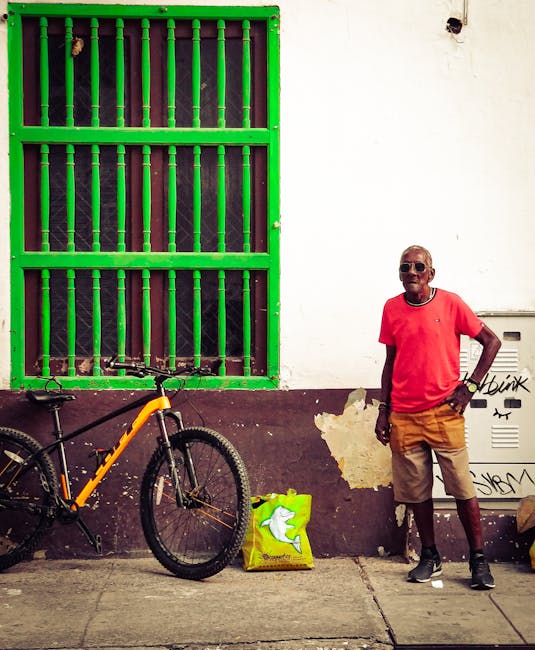 A vibrant street scene in Cartagena featuring a man and a bicycle beside a colorful wall.