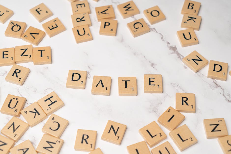 Wooden letter tiles scattered on a marble surface, spelling out 'DATE'.