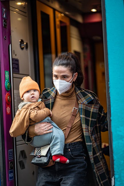 Woman wearing a face mask carries her baby on a train, showcasing modern urban life.
