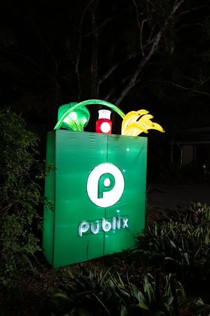 Glowing Publix sign with vegetables, captured outdoors at night.
