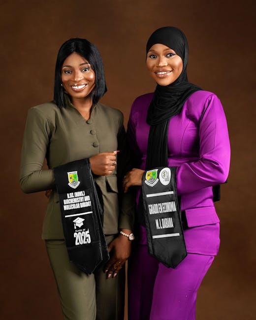 Two smiling women in graduation attire celebrating their success.