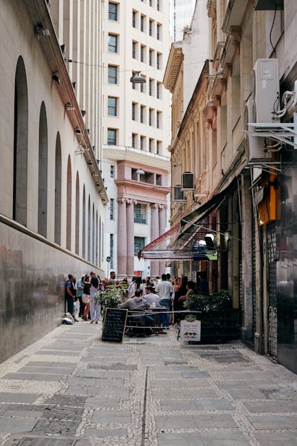 A bustling city alley with outdoor cafes and people enjoying the urban setting.