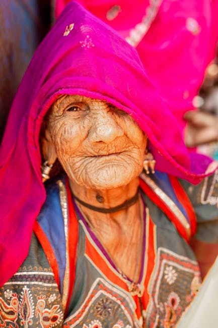 Portrait of an elderly Indian woman in bright traditional clothing and pink headscarf, Pushkar, India.