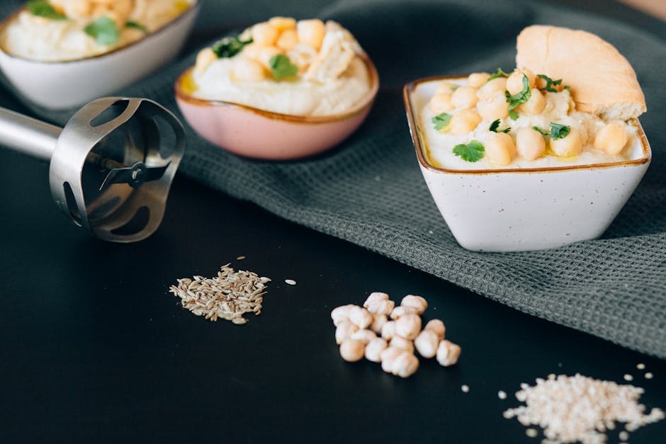 Delicious creamy hummus garnished with chickpeas and herbs, presented in a modern kitchen setting.