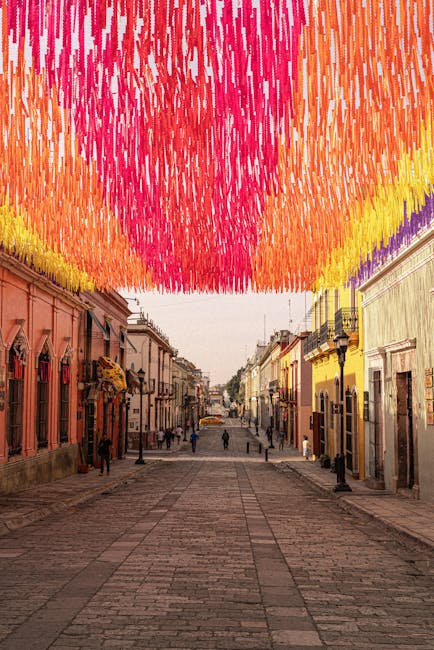Vibrant street with colorful decorations overhead in Oaxaca, Mexico, showcasing local culture and architecture.