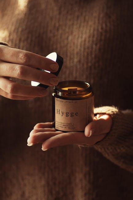 Warm candlelight captured as a wooden cap reveals 'Hygge' candle, perfect for fall coziness.