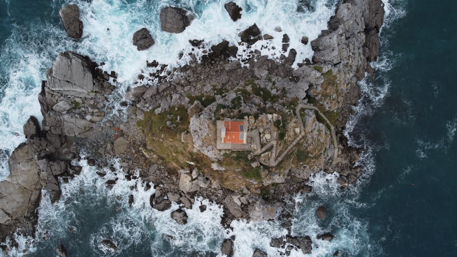 Stunning aerial shot of a coastal cliff in Montenegro, featuring rocky terrain and crashing waves.
