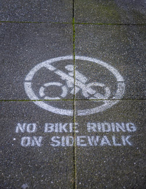 Close-up of a 'No Bike Riding' sign painted on a sidewalk.