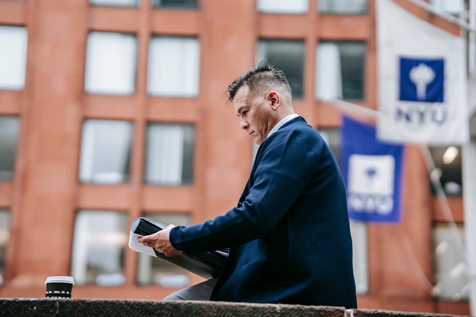 Businessman reviews documents outside with a tablet in a city setting.