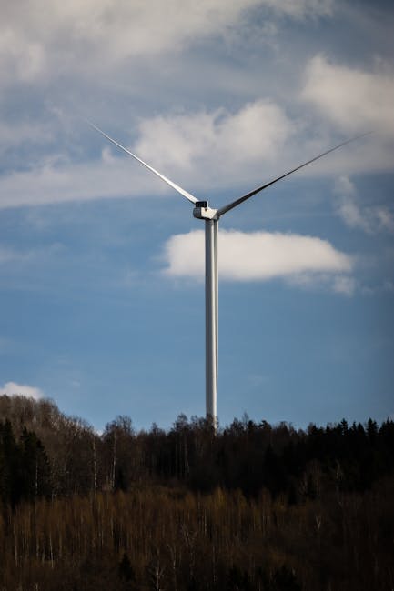 A wind turbine standing tall against a clear blue sky in rural Jönköping, Sweden.