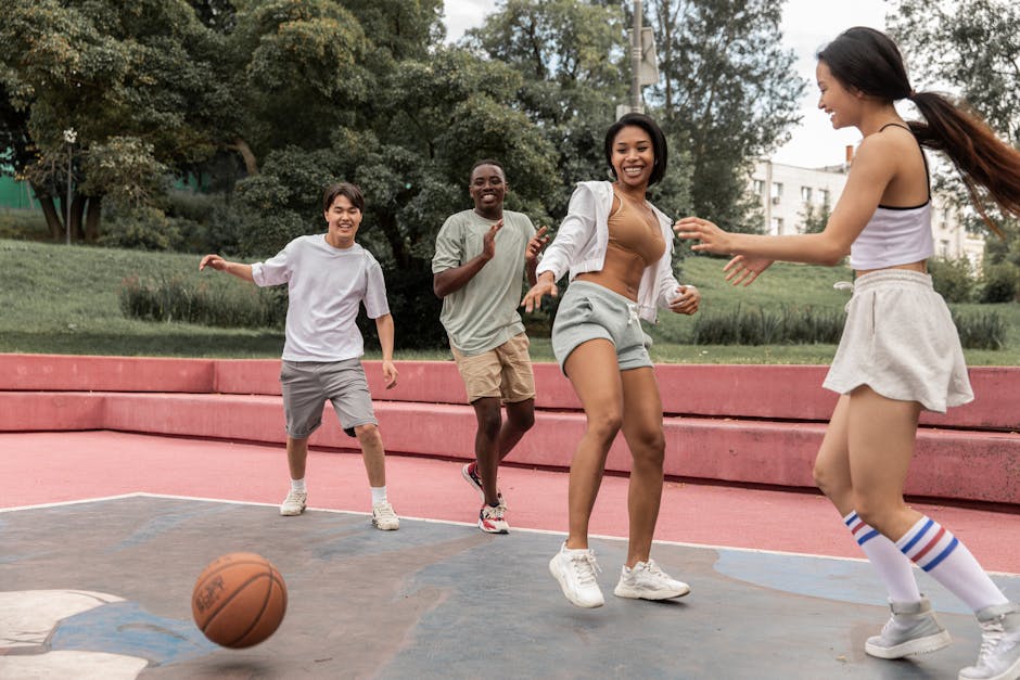 A group of diverse young adults playing basketball outdoors, laughing and having fun.