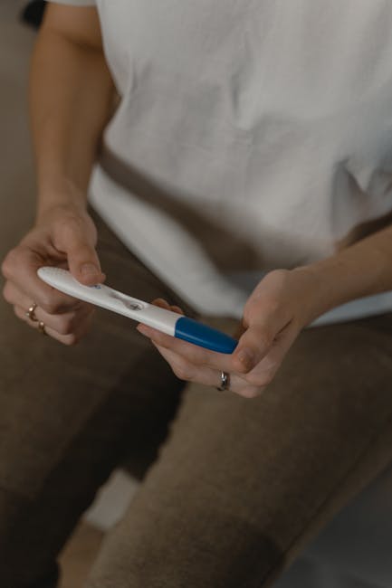 Close-up shot of a woman holding a pregnancy test, displaying anticipation and emotion.