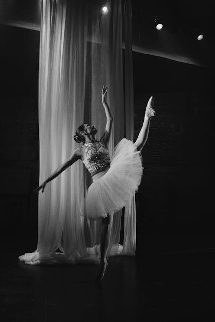 Graceful ballet dancer posing in a dramatic black and white studio setting.