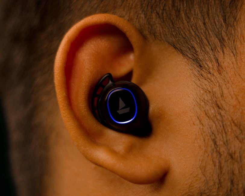 Close-up view of a wireless earbud fitted in a human ear showcasing modern audio technology.