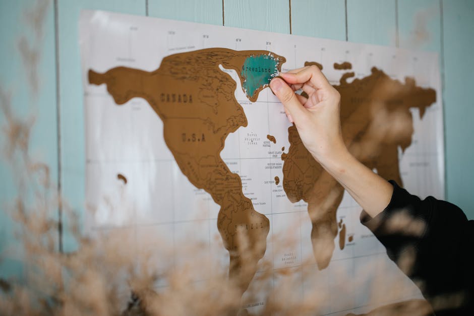 A hand scratches off a world map, revealing countries visited, symbolizing travel adventures.