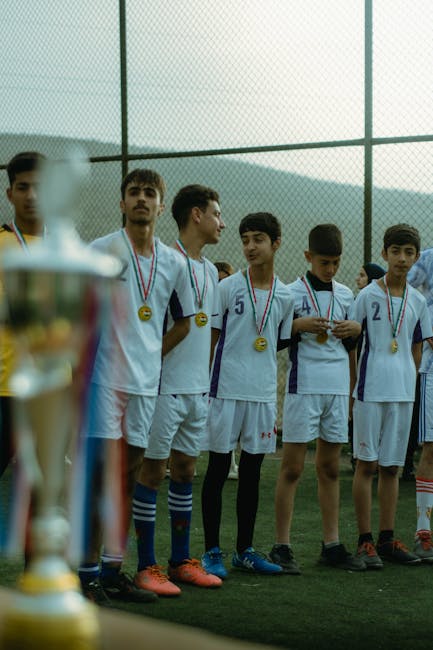 Teenage soccer team in Erbil celebrating victory with medals on outdoor field.