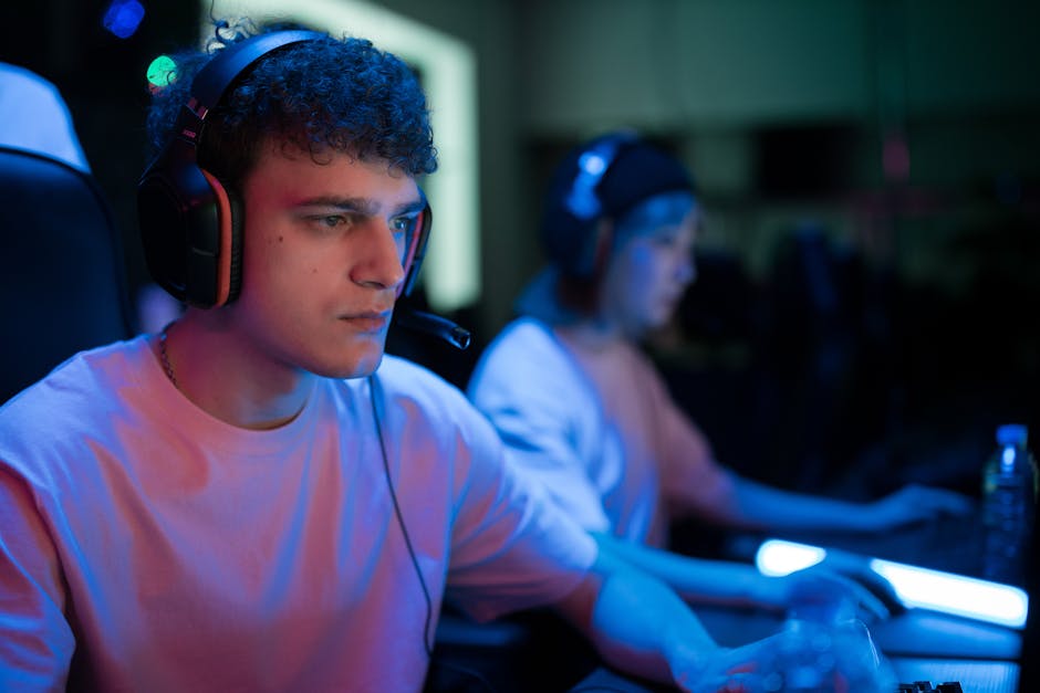 Man with headset engaged in intense gaming session under neon lights.