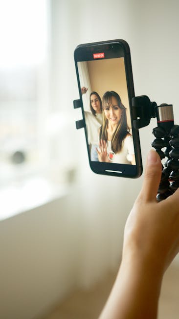 Two young women are taking a joyful selfie using a smartphone indoors, capturing a happy moment.