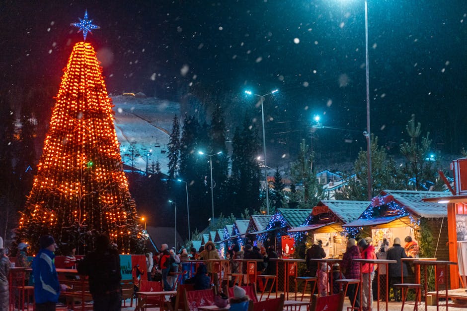 Illuminated Christmas tree and market stalls in snowy Bukovel, Ukraine during winter festivities.