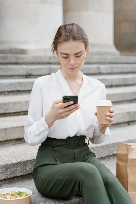 Woman wearing eyeglasses with coffee and smartphone on steps. Casual and modern urban setting.