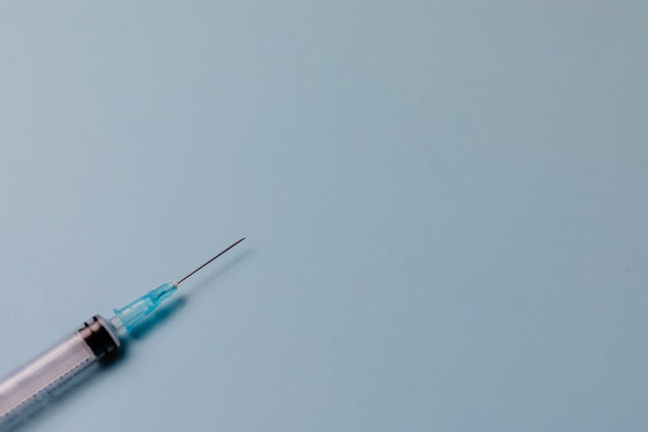 Detailed shot of a syringe against a pastel blue surface, ideal for medical themes.