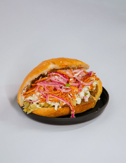 Delicious Mexican torta sandwich filled with fresh pickled vegetables on a black plate.