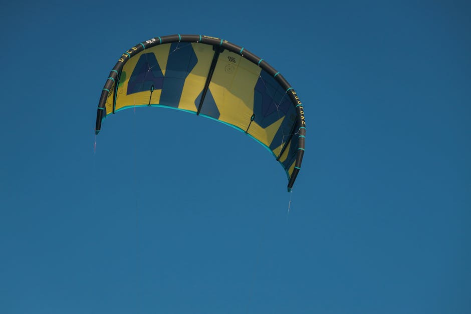Colorful kitesurf sail in vibrant flight against clear blue sky in Denmark, capturing the essence of wind sports.
