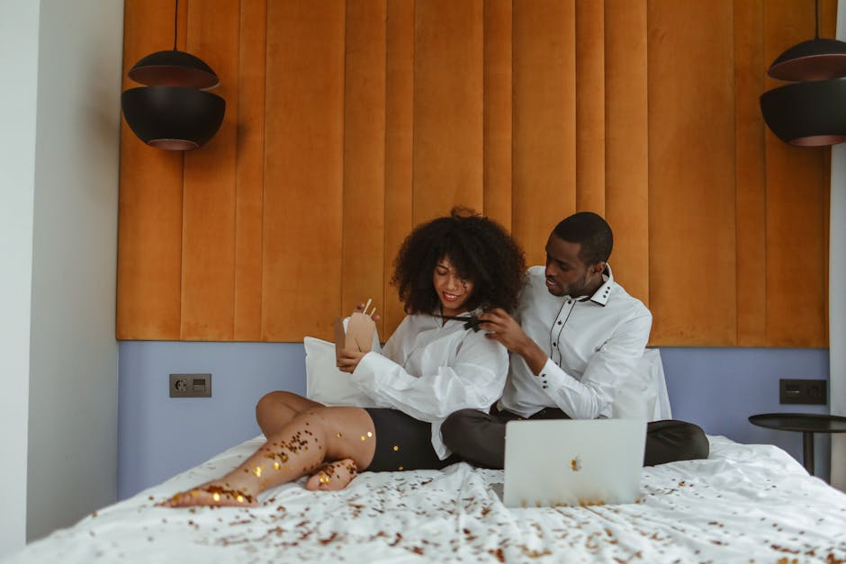 A loving couple enjoys quality time together in a stylish hotel room with a laptop and takeaway food.