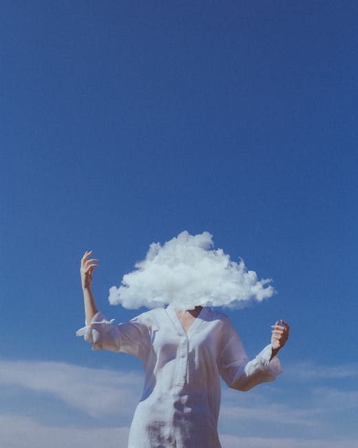 A surreal image of a woman with a cloud in place of her head against a bright blue sky.